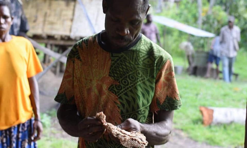 A neighbor in Papua New Guinea holding food during a community gathering