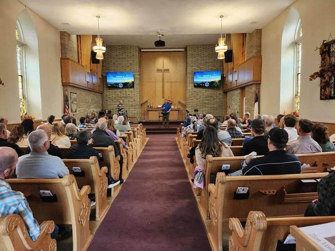 Tim Carmical speaking from the front of a church sanctuary